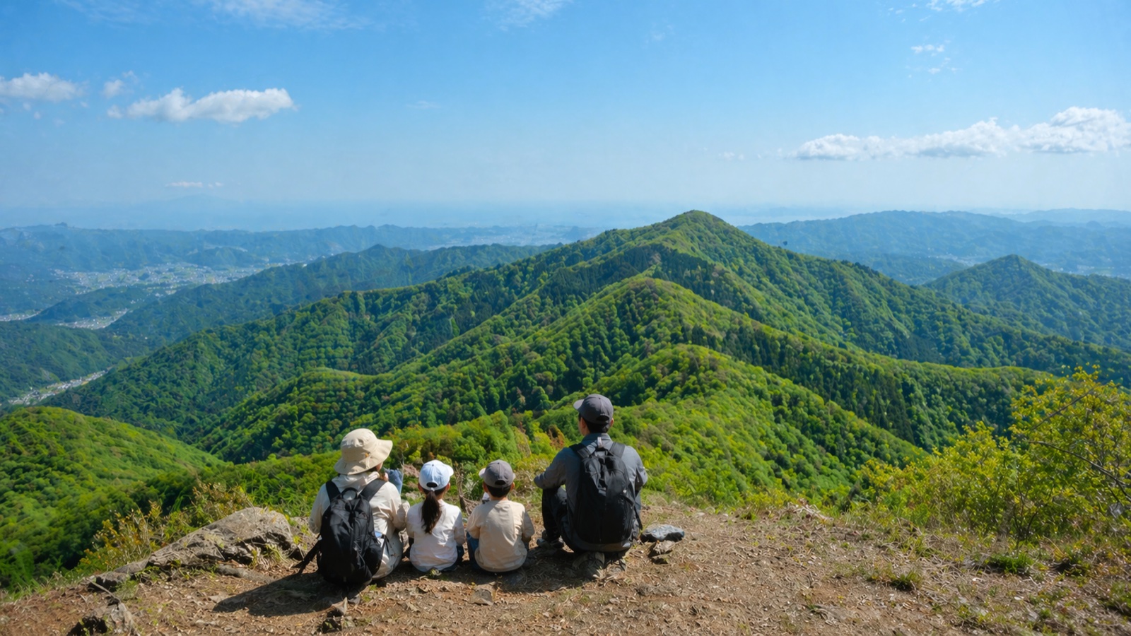 関東の山の稜線から見た5月の新緑の山並みと子連れハイカー