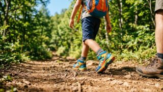 子ども用登山靴を履いて登山道を歩く子どもと親の足元