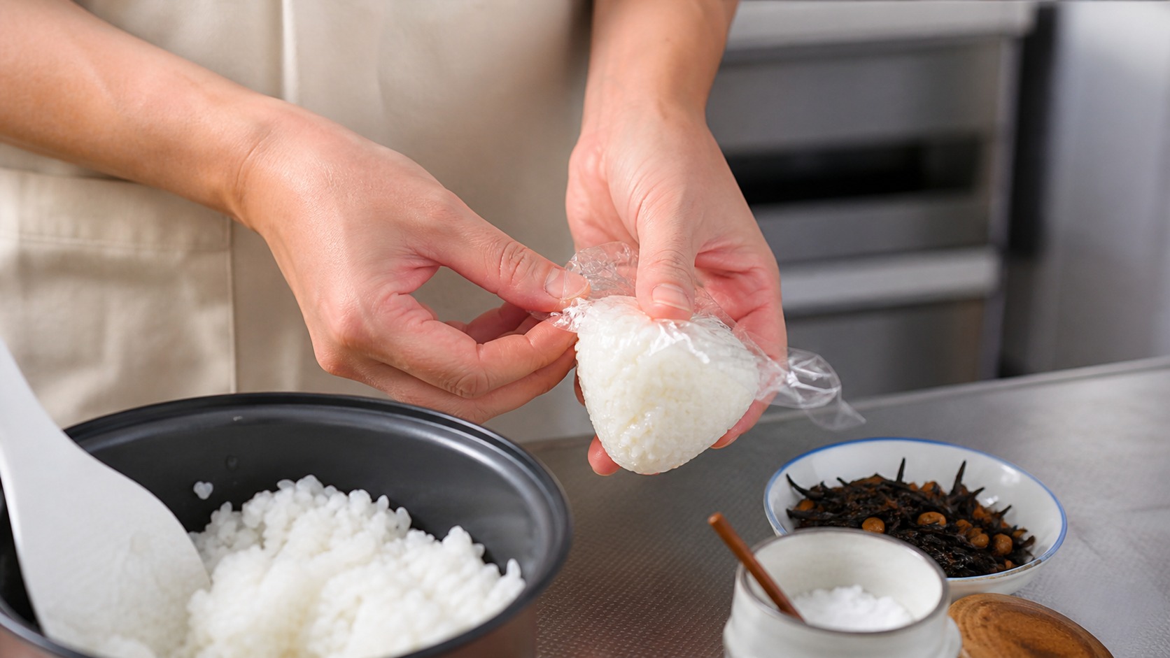 キッチンでラップを使っておにぎりを握る手元