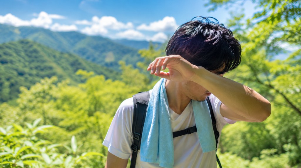 夏の登山道で汗をぬぐう登山者