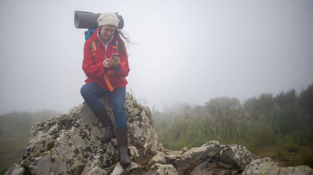 山でスマートフォンを操作する登山者