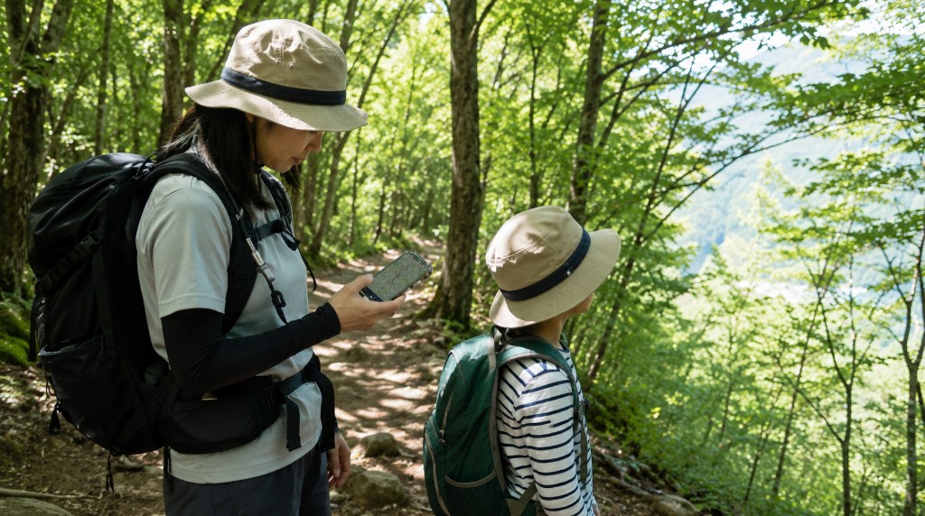 登山道でスマホの地図アプリを見る親子と電池残量の心配