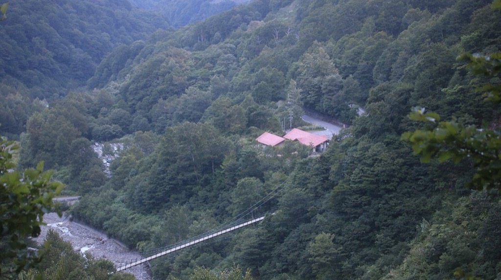別当出合の全景。赤い屋根の休憩舎と柳谷川の吊り橋、左手に駐車場