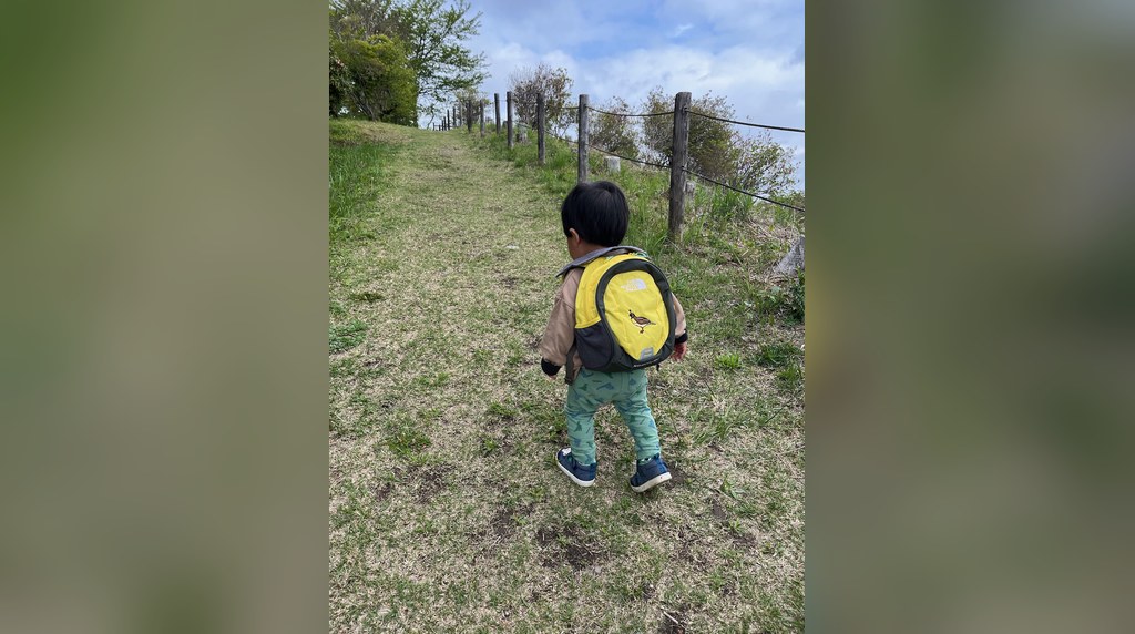 草の道を登る子どもの後ろ姿