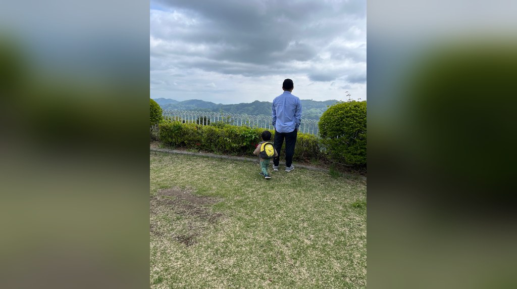 フェンス越しに秩父の山並みを眺める親子