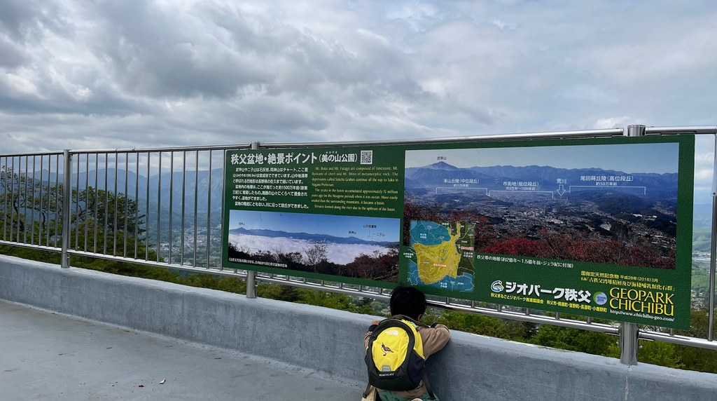 展望ポイントの案内板の前から下界を見下ろす子ども