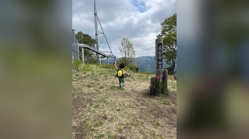 美の山の山頂の標柱へ歩いていく子ども
