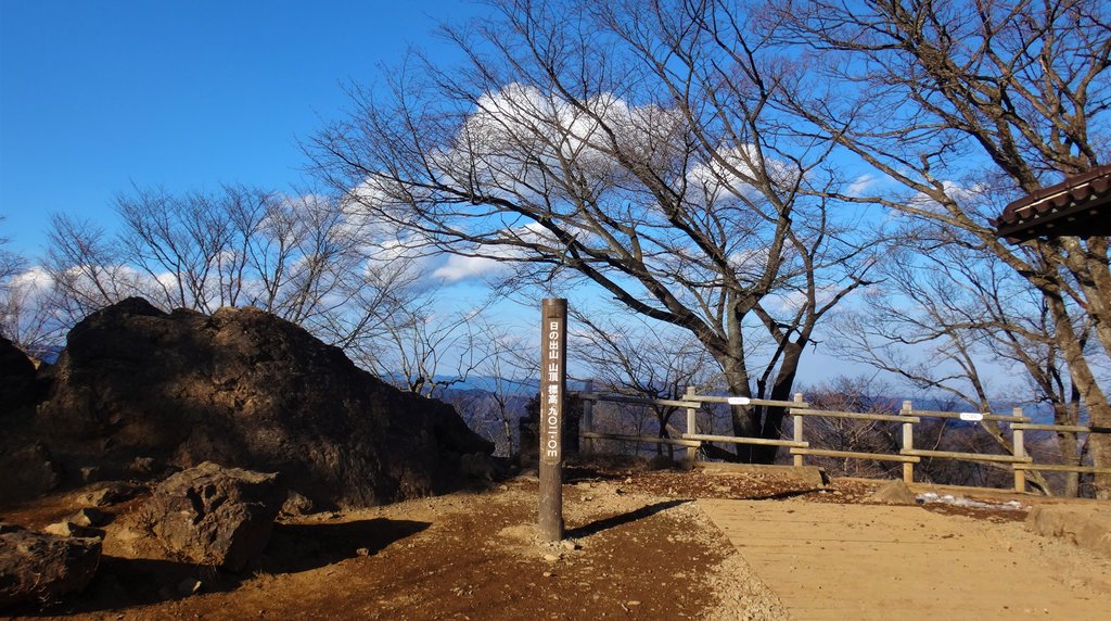 日の出山の山頂の標柱と岩、冬の青空