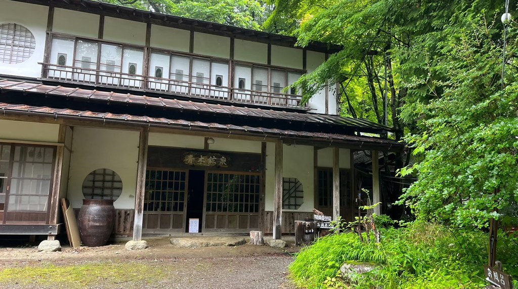 木造の温泉旅館の建物と新緑