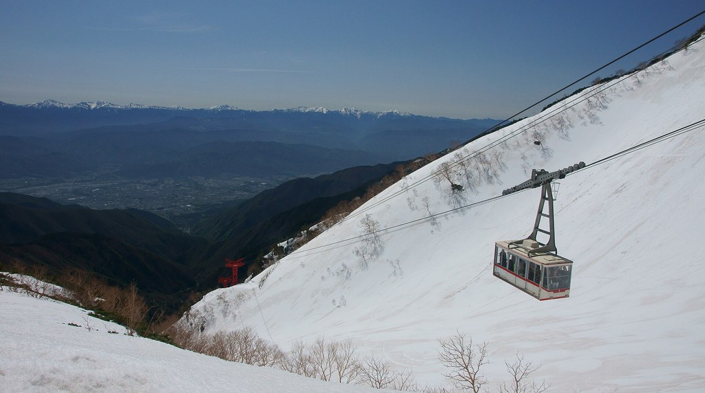 残雪の斜面の上を進む駒ヶ岳ロープウェイのゴンドラ