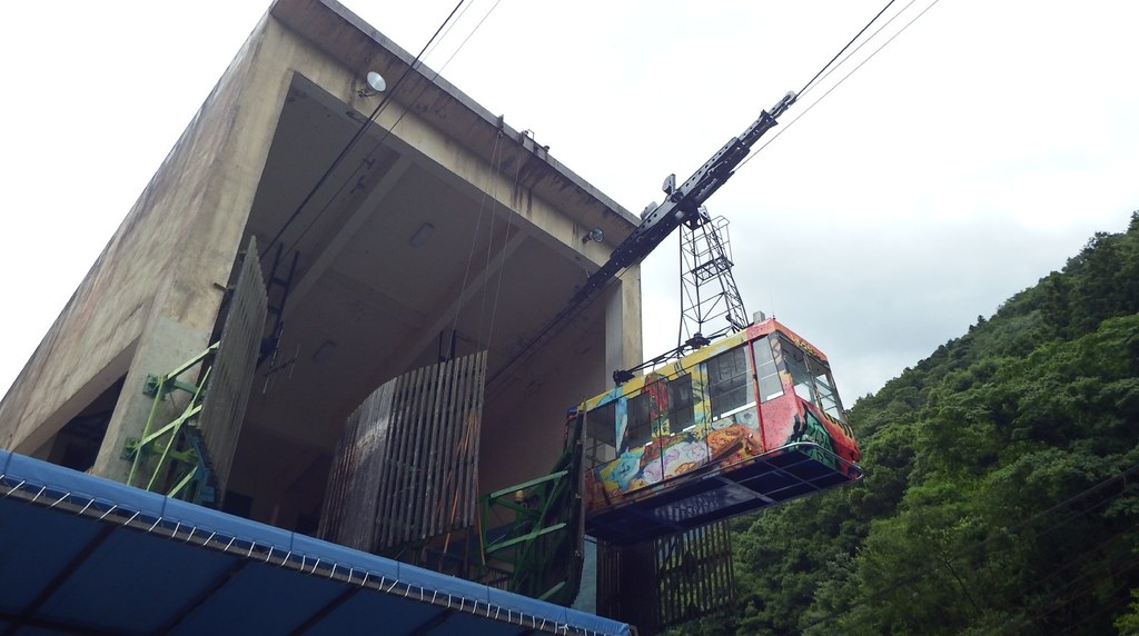 山の斜面に張り出した石鎚登山ロープウェイの山麓下谷駅と、出ていくゴンドラ