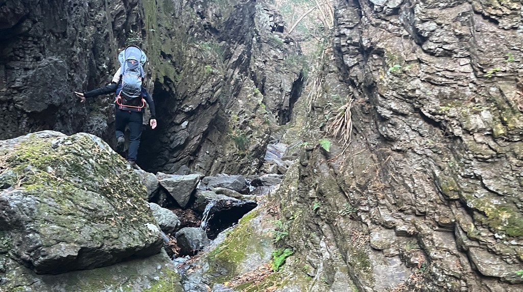 岩の間の沢沿いを登る登山者